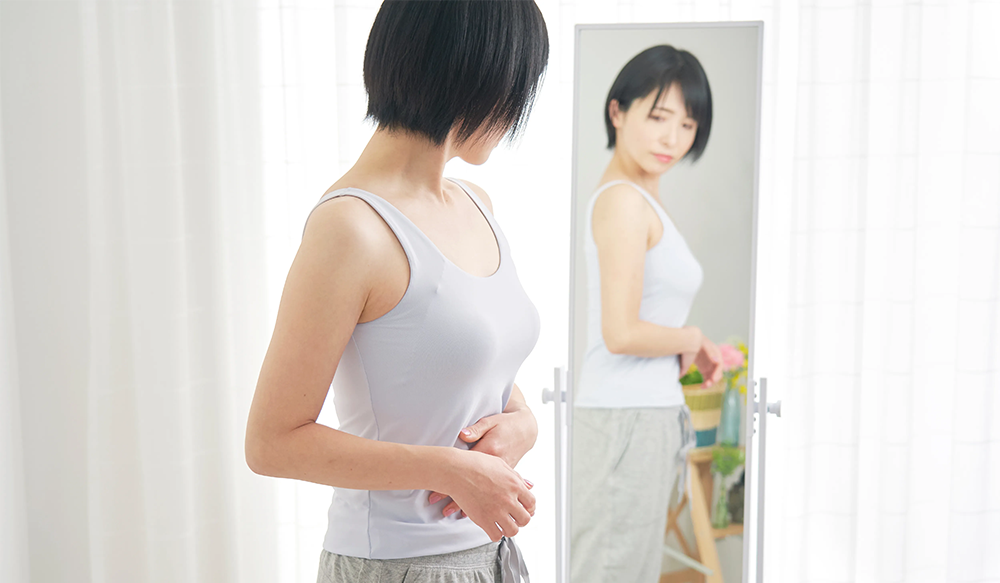 お腹周りが気になって鏡を見ている女性