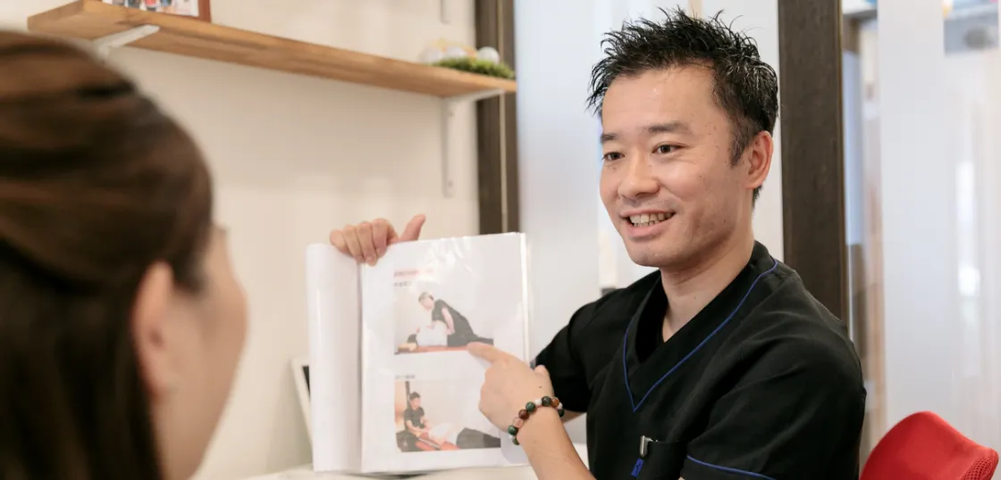 女性に資料を見せながら説明する整体師